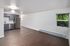 Bright and modern open-plan kitchen and living space featuring sleek gray cabinetry, stainless steel appliances, and elegant wood flooring.