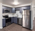 Modern kitchen with sleek stainless steel appliances, elegant dark cabinetry, and stylish flooring, perfect for gourmet cooking.