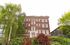 Charming brick apartment building with lush green surroundings and classic architectural design.