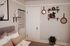 Charming bedroom corner with cozy pillows, elegant wall art, and stylish wooden shelves featuring plants and decor.