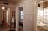 Welcoming apartment hallway with elegant decor, leading to a cozy bedroom and stylish bathroom, featuring warm lighting and polished wood floors.