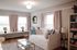 Sunlit living room with elegant decor, featuring a cozy white daybed, vibrant throw pillows, and a chic coffee table, perfect for relaxation.