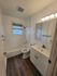 Elegant bathroom with modern fixtures, featuring a full bathtub, sleek vanity, and stylish wood flooring.