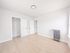Bright empty room with sleek hardwood flooring, modern light fixture, and ample closet space, perfect for customization.