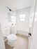 Bright and modern bathroom featuring elegant white fixtures, a sleek vanity, and a refreshing bathtub under natural light.