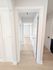 Bright, inviting hallway featuring light wood flooring and sleek white doors, leading to spacious rooms.