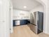 Modern kitchen with elegant navy and white cabinetry, featuring a sleek stainless steel refrigerator and dishwasher, set against a light wooden floor.