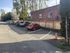 Charming parking area with neatly marked spaces adjacent to a stylish brick building, surrounded by lush greenery and wooden fencing.