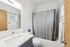 Bright and modern bathroom featuring a sleek white vanity, contemporary faucet, and elegant gray shower curtain.