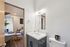 Modern bathroom with sleek fixtures and view into a cozy bedroom workspace featuring stylish decor and warm wood flooring.