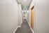 Bright, welcoming apartment hallway with modern design and clean lines, featuring polished wooden doors and soft lighting.