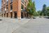 Charming urban corner featuring a modern brick building with a vibrant street in the foreground, ideal for city living.