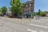 Charming urban street view with vibrant storefronts, lush trees, and lively pedestrian activity, capturing the essence of city living.