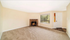Inviting living room with a cozy fireplace, plush carpet, and a large window offering serene views.
