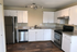 Modern kitchen with sleek stainless steel appliances, elegant white cabinetry, and stylish wood flooring.