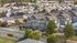 Charming aerial view of a picturesque neighborhood with modern townhouses surrounded by lush greenery and scenic streets.