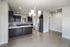 Modern, open-plan kitchen with elegant dark cabinetry, sleek stainless-steel appliances, and a stylish chandelier accentuating the space.