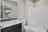 Modern bathroom with elegant fixtures, featuring a sleek vanity mirror and a spacious shower, offering a serene and stylish ambiance.