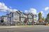 Modern townhouse complex with beautiful architecture and manicured landscaping, set against a clear blue sky.