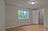Bright and airy bedroom with hardwood floors, featuring a large window with a view of lush greenery and ample closet space.