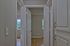 Inviting hallway with wooden flooring, leading to a bright room with large windows and ample natural light.
