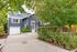 Charming blue house with lush landscaping and spacious driveway.