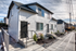 Charming white townhouse with modern black doors and landscaped entry, set against a bright sky, offering bright and inviting living spaces.