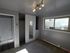 Bright bedroom featuring a spacious closet with mirrored sliding doors, modern overhead track lighting, and a large window offering natural light.