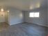 Spacious living area with modern gray laminate flooring and large window offering abundant natural light.