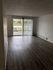 Bright and inviting living room with sleek laminate flooring and large sliding glass doors opening to a private balcony.
