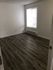Bright, spacious bedroom featuring elegant wood flooring and a large window with natural light.