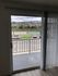 Inviting apartment view showcasing a balcony with elegant railing, overlooking a serene landscape and vibrant trees, perfect for relaxation.