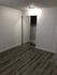 Chic bedroom space with elegant wooden flooring and mirrored closet doors, offering a modern and spacious feel.