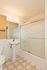 Bright and inviting bathroom featuring a sleek pedestal sink, modern lighting, and a stylish glass-enclosed bathtub with tile flooring.