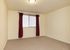 Bright and spacious room with plush carpeting and elegant red curtains, perfect for a cozy retreat.