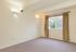 Bright and inviting room with plush carpeting, neutral walls, and a large window framed by elegant curtains, ideal for creating a cozy living or bedroom space.