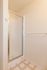 Modern bathroom corner with sleek glass shower door, neutral tile flooring, and bright white walls.