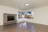 Bright and inviting living room featuring a cozy fireplace, expansive hardwood floors, and large corner windows offering scenic views.