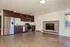 Modern kitchen with stainless steel appliances, rich wooden cabinetry, and a cozy brick fireplace in an open-concept layout.