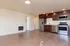 Modern apartment kitchen with stainless steel appliances, sleek wood cabinetry, and spacious open floor layout.