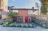 Charming brick apartment with vibrant red door, surrounded by lush landscaping and modern design elements.