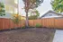 Tranquil backyard featuring lush greenery, a majestic tree, and a charming wooden fence, perfect for relaxation and outdoor enjoyment.