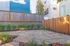 Charming outdoor patio with modern paving stones, lush plants, and a wooden privacy fence, ideal for relaxation.
