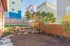 Charming backyard with landscaped garden, rustic stone pathway, and thriving trees, enclosed by a stylish wooden fence.