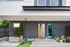 Chic modern apartment entrance with vibrant blue doors, stylish vertical siding, and lush potted plants creating a welcoming atmosphere.