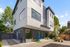 Contemporary three-story home with large windows, stylish facade, and inviting outdoor patio in a lush setting.
