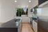 Modern kitchen with sleek gray countertops, stainless steel appliances, and a bright window view of lush greenery.