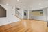 Bright modern interior with sleek wooden floors, open staircase, and ample natural light from large windows.