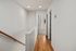 Bright hallway with elegant wooden flooring leading to a spacious, sunlit bedroom in a modern apartment.