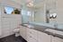 Elegant modern bathroom featuring sleek double sinks, a large mirror, and a bright window view.